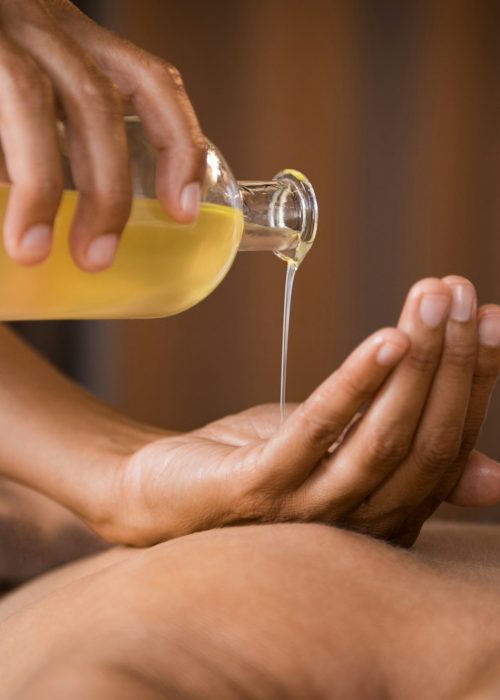 Therapist pouring massage oil at spa